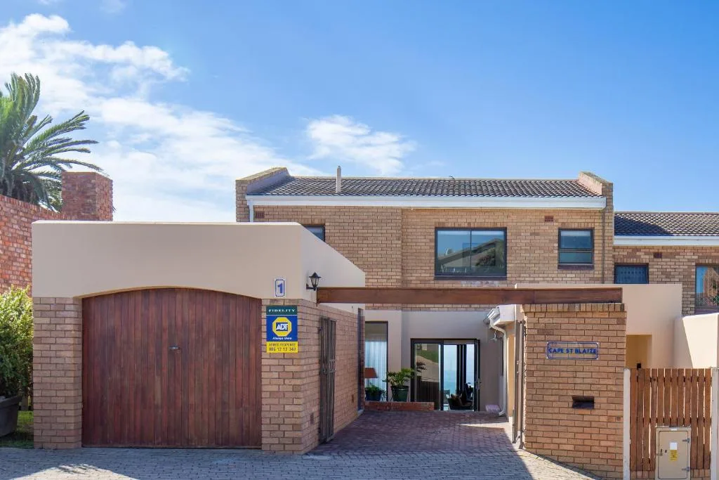 Modern brick holiday home with garage, patio entrance, and palm tree