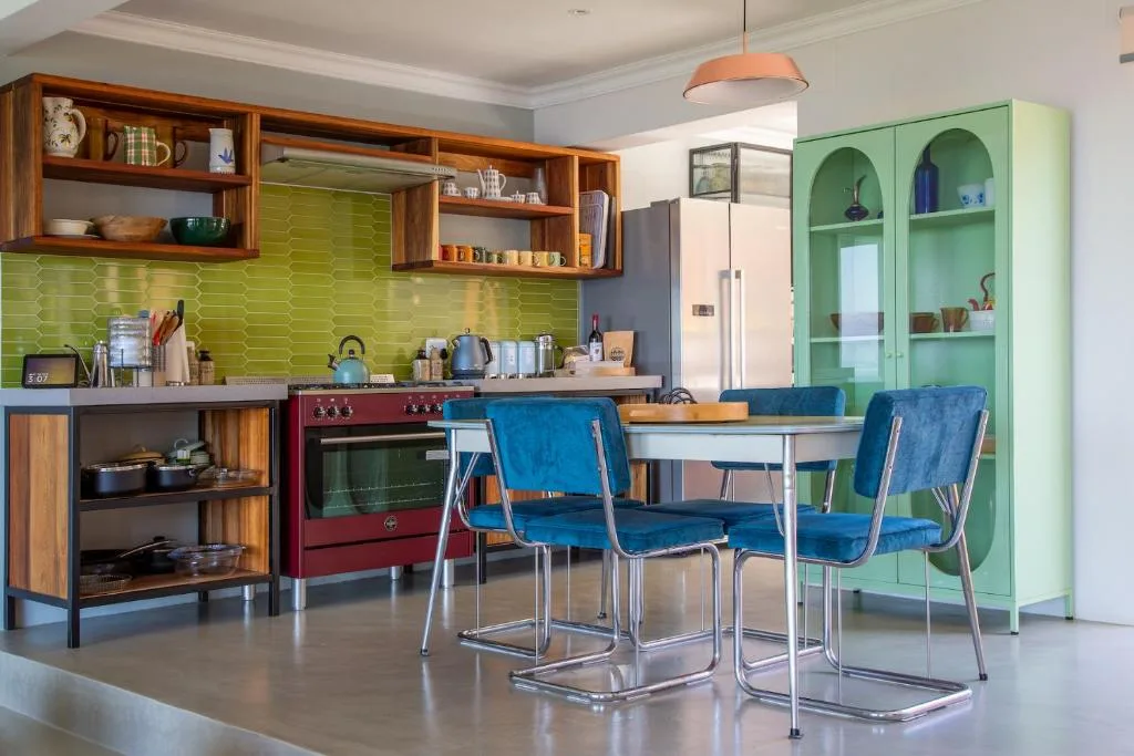 Retro kitchen with lime green backtile, red stove, and wooden cabinetry