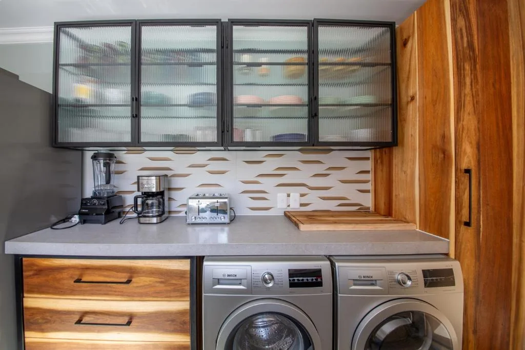 Modern kitchen with dual washers, white countertop, and glass-fronted cabinets