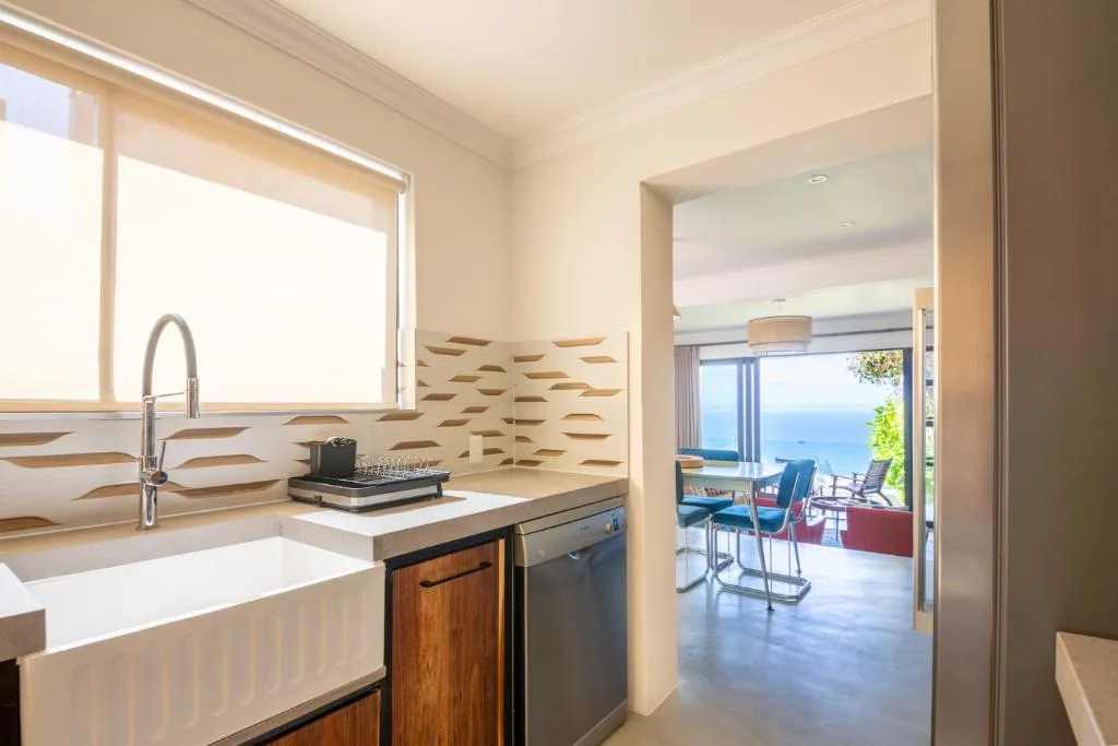 Modern kitchen with white sink, dark cabinetry, and ocean view through open doorway