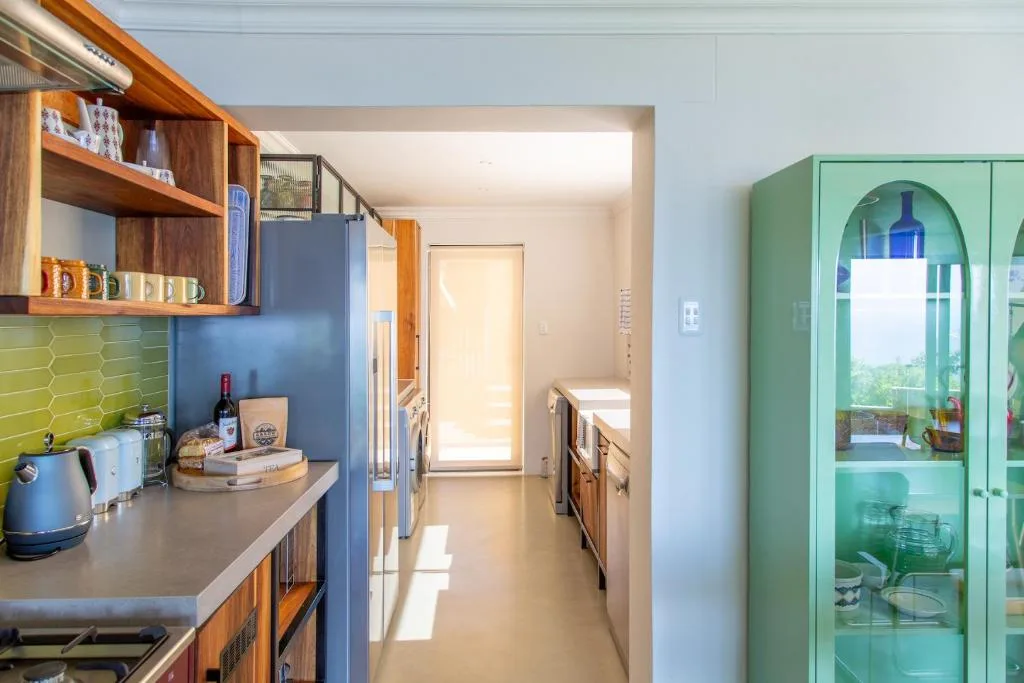 Modern kitchen with blue accent wall, wooden cabinetry, and green display cabinet