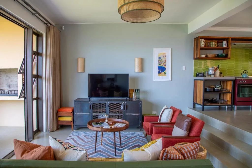 Modern lounge with red armchairs, TV unit, and colorful geometric rug