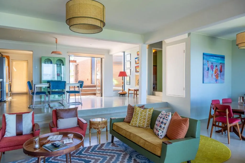 Bright open-plan lounge with colorful mid-century furniture and ocean views