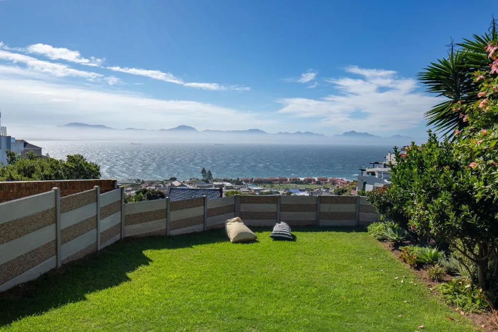 Expansive ocean and mountain vista from elevated garden with coastal town below