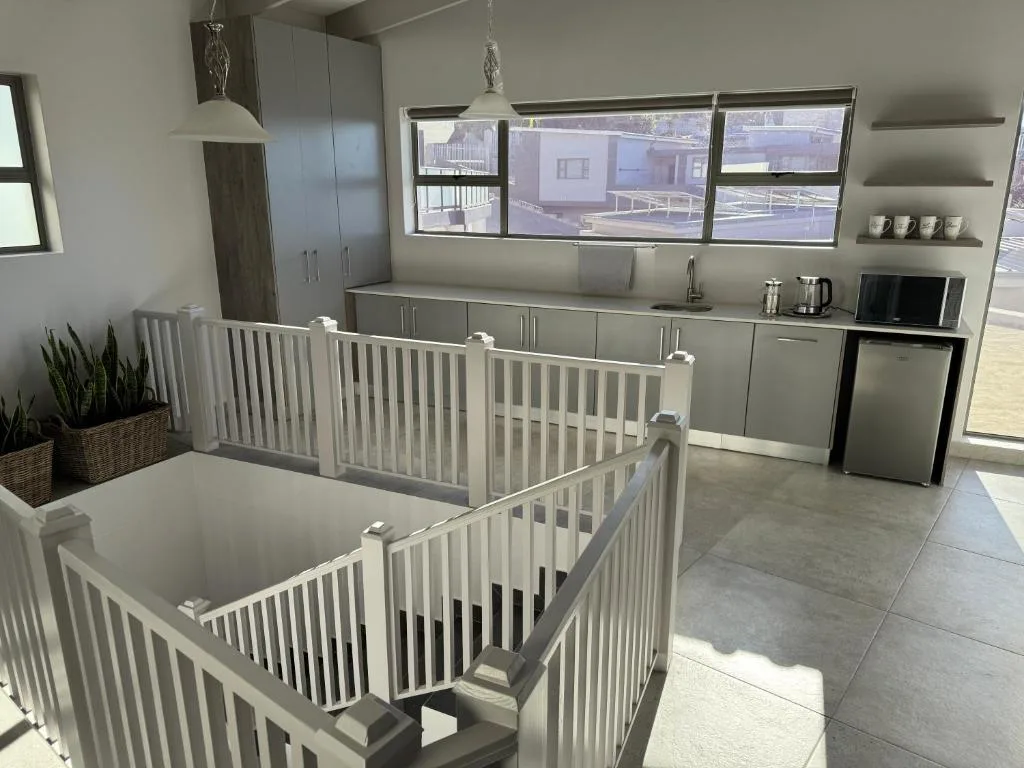 Modern kitchen with stainless steel appliances and gray cabinetry overlooking deck