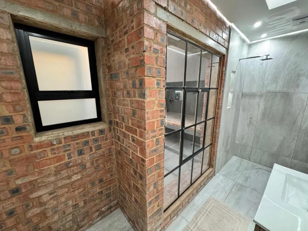 Modern bathroom with glass shower enclosure and brick feature walls