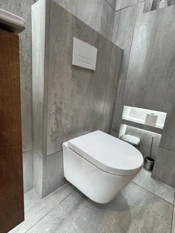 Modern bathroom with wall-mounted toilet and gray tile walls