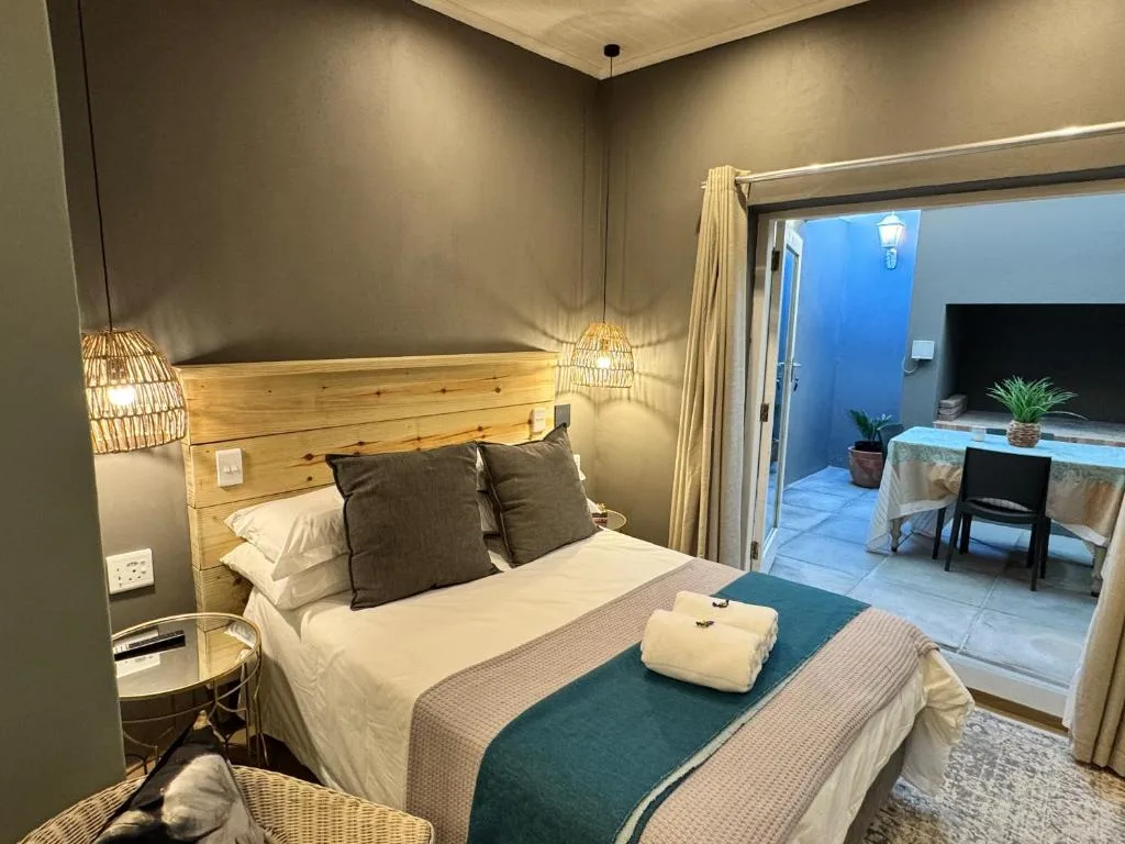 Modern bedroom with wooden headboard, pendant lights, and ocean view access