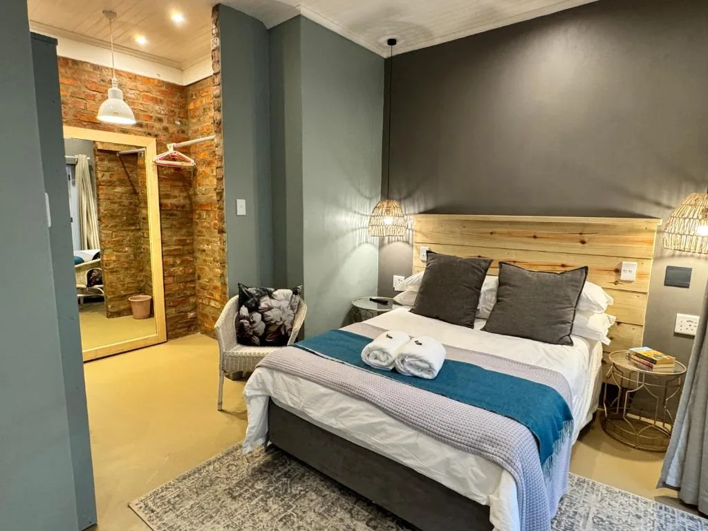 Modern bedroom with wooden headboard, fresh white bedding, and en-suite bathroom view