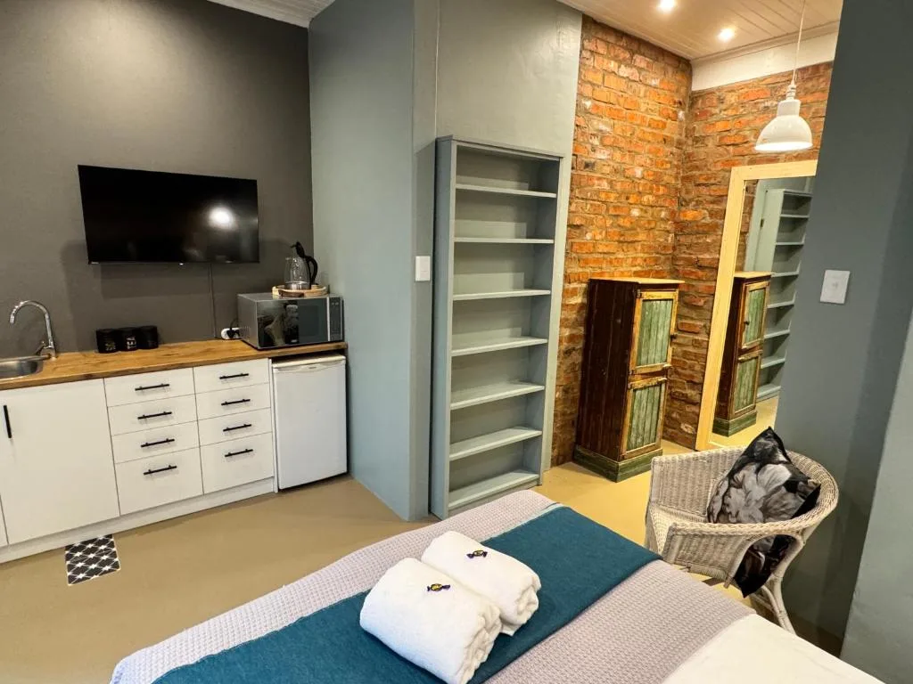 Modern bedroom with kitchenette, exposed brick, and contemporary furnishings