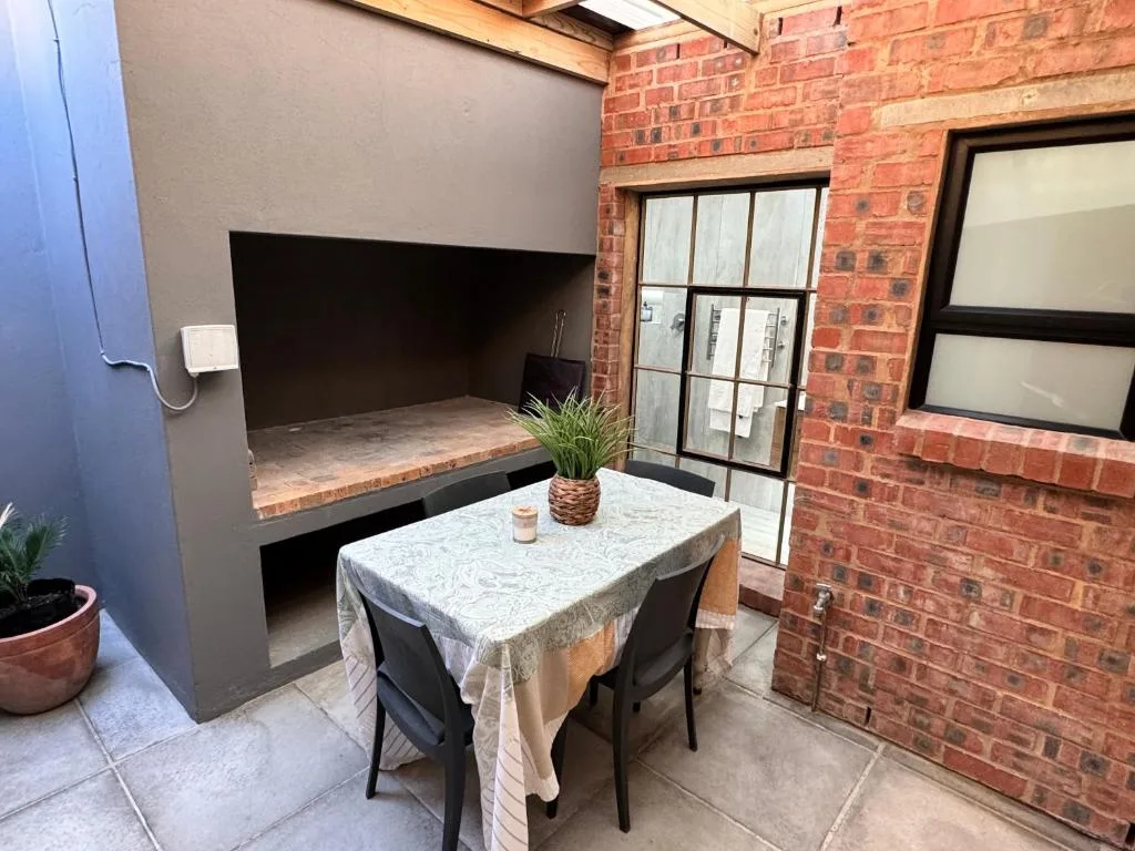 Outdoor patio area with small dining table and built-in braai fireplace