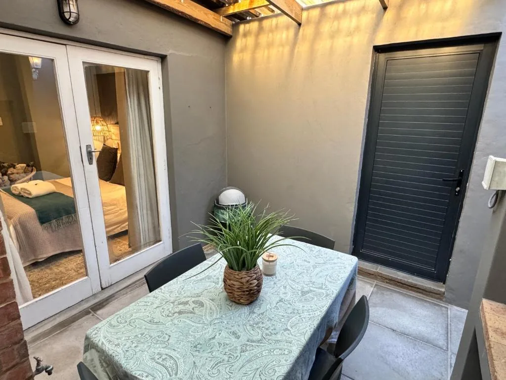 Covered outdoor patio with dining table and potted plant near bedroom