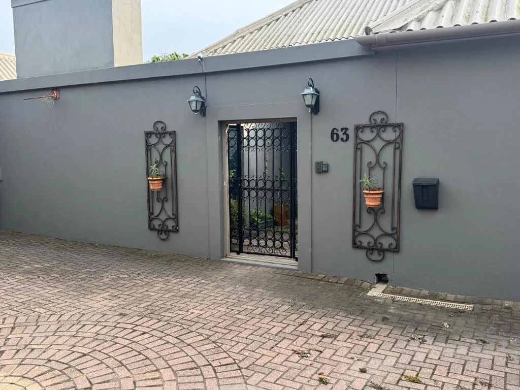Modern gray facade with ornate iron door and decorative wall sconces