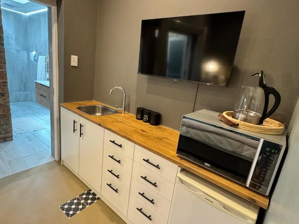 Modern kitchenette with wooden countertop, sink, microwave, and wall-mounted TV
