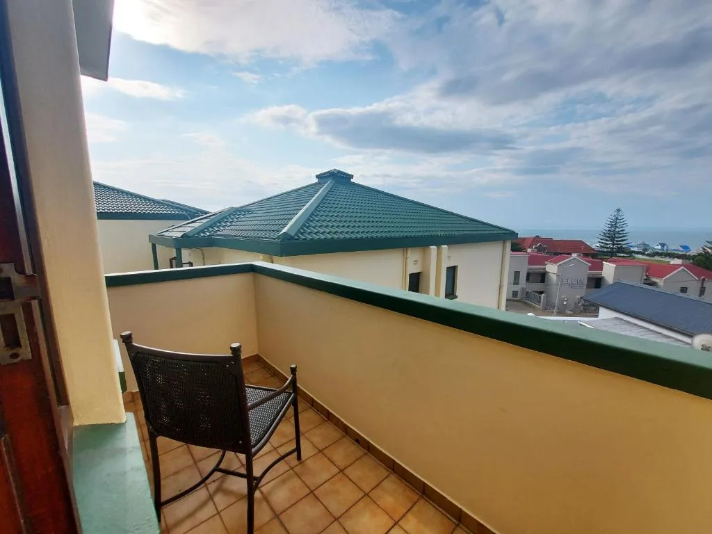 Balcony with single chair overlooking coastal town and houses