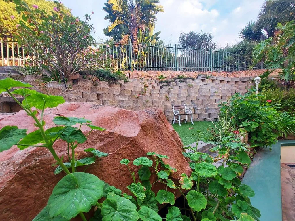 Lush garden area with retaining wall, seating, and palm trees