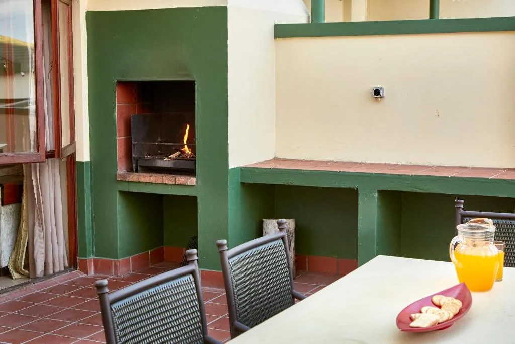 Outdoor patio with fireplace, dining table, and garden views