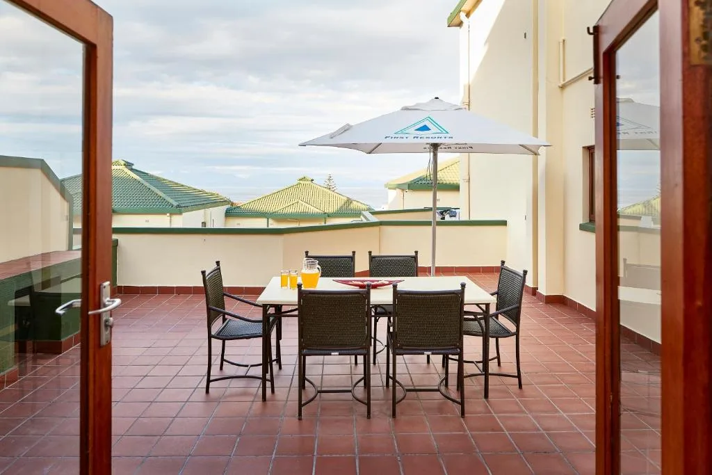 Rooftop terrace with dining table, umbrella, and surrounding buildings