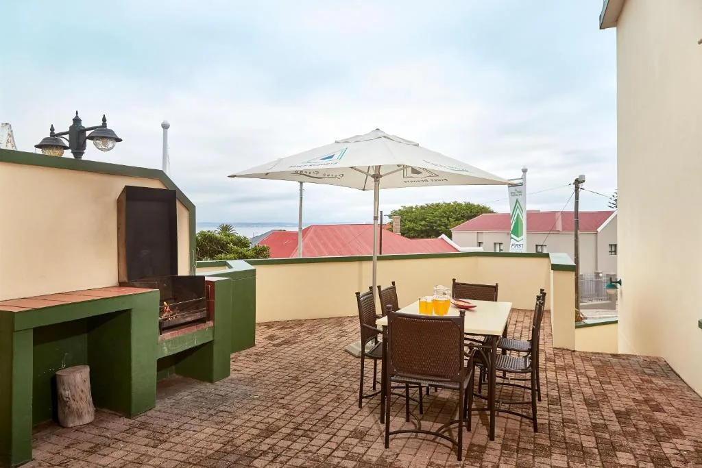 Rooftop deck with dining table, umbrella, and braai area overlooking town