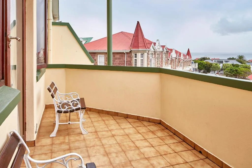 Spacious balcony with seating overlooking historic Mossel Bay architecture and ocean