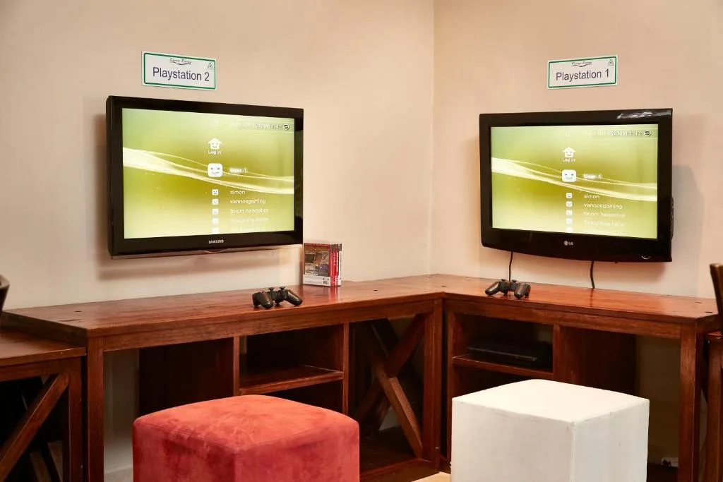Gaming setup with two wall-mounted screens and wooden desks