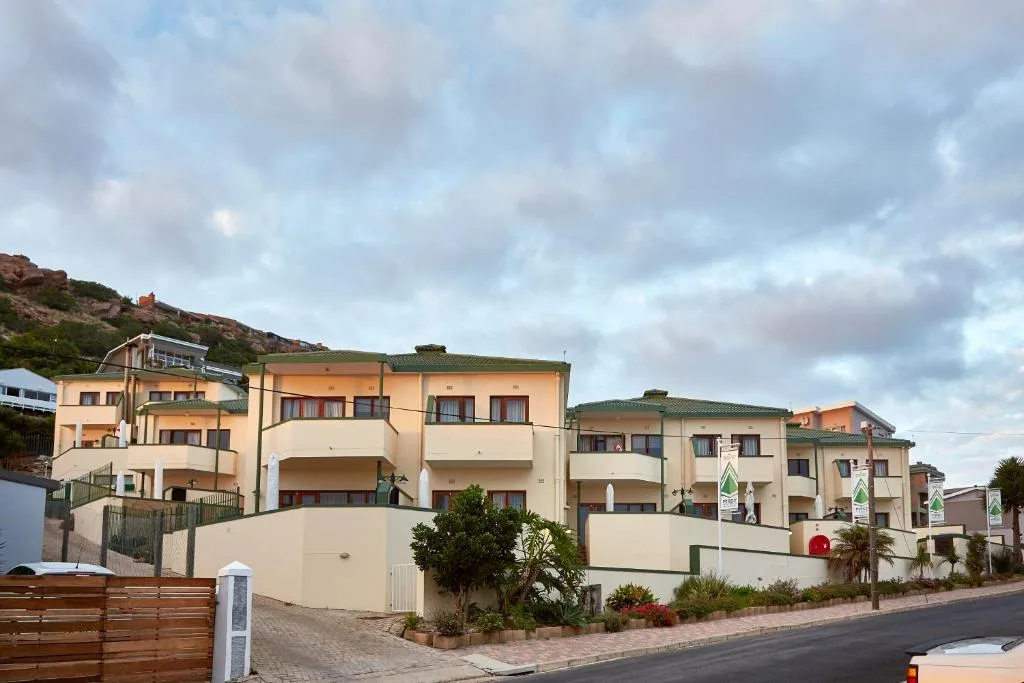 Cream-colored apartment complex on hillside with green roofs and balconies