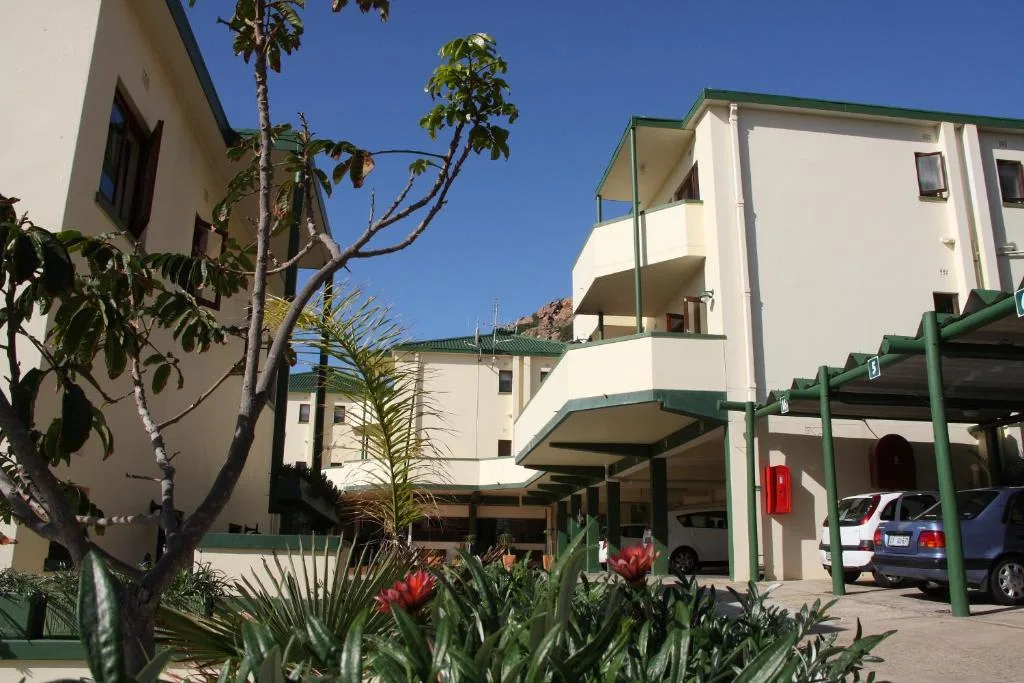 Modern white apartment building with green carports and landscaped gardens