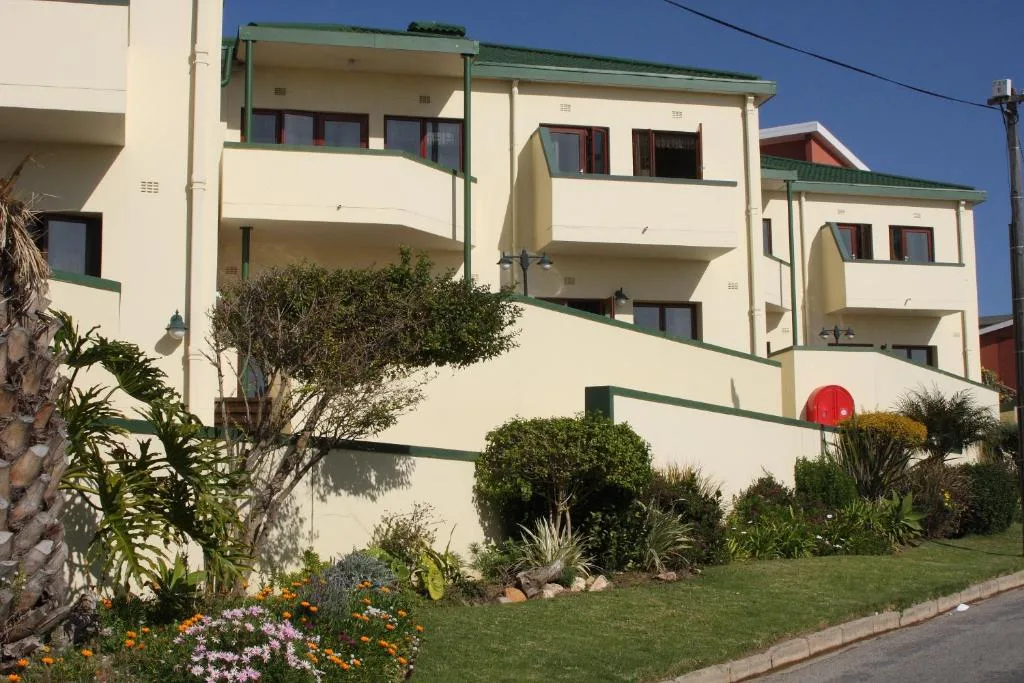 Modern cream and green apartment building with manicured gardens and flowering plants