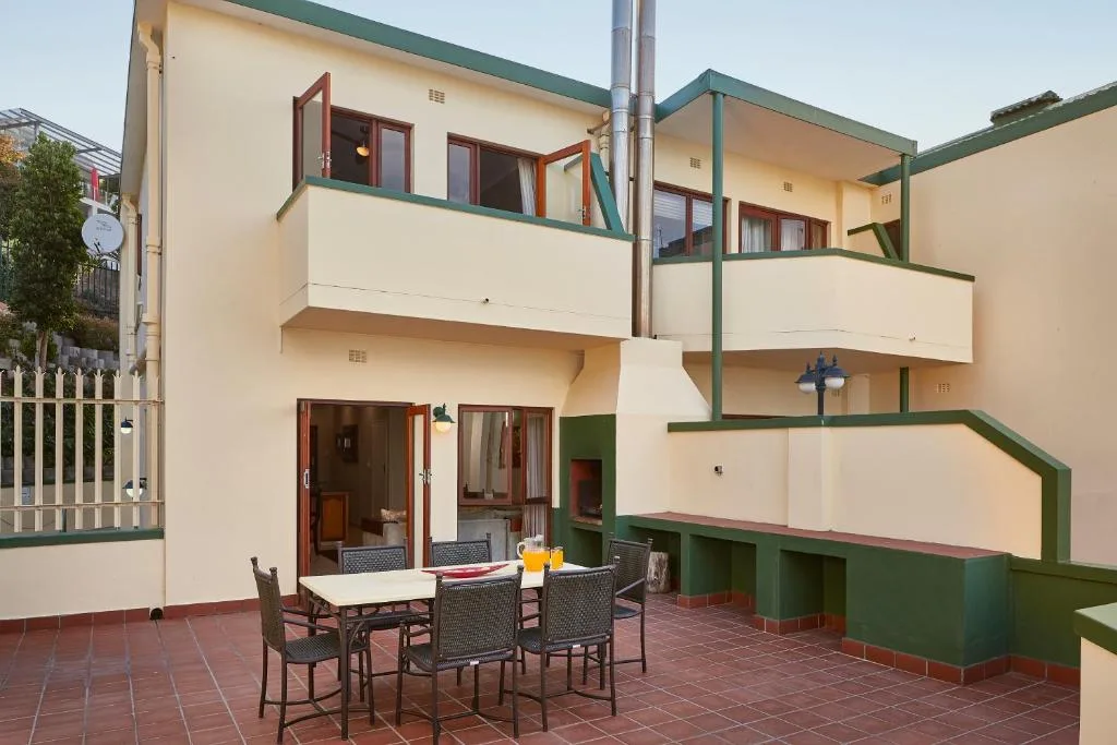 Modern cream and green multi-level building facade with outdoor dining area