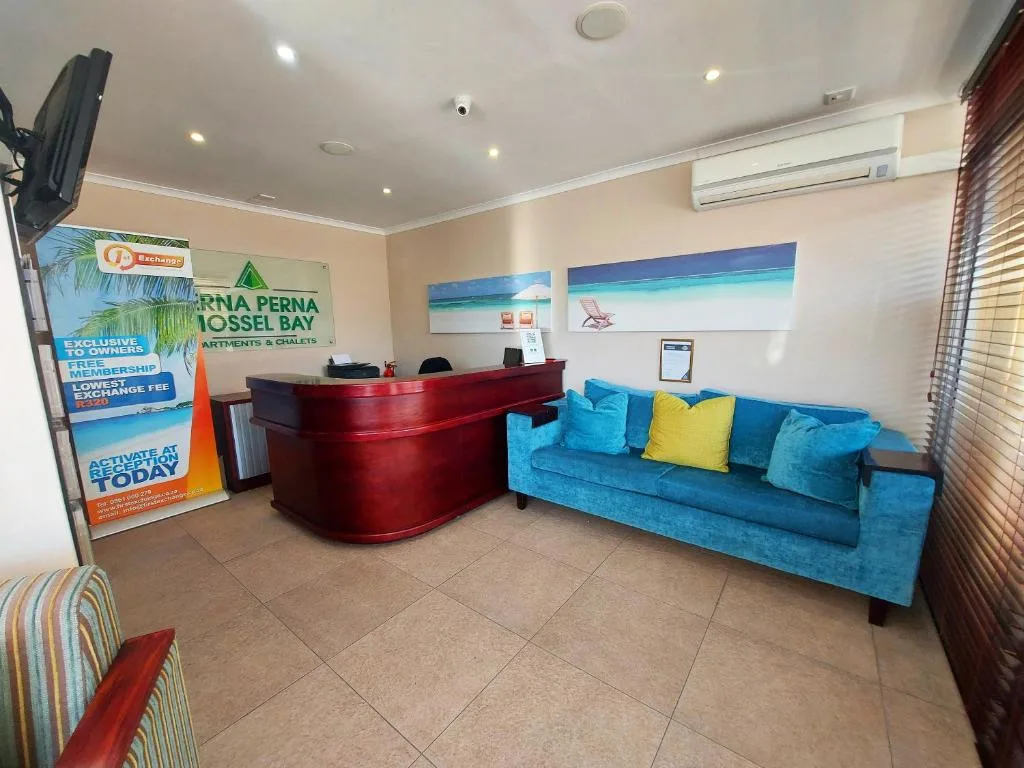 Bright lounge with turquoise sofa, reception desk, and coastal artwork