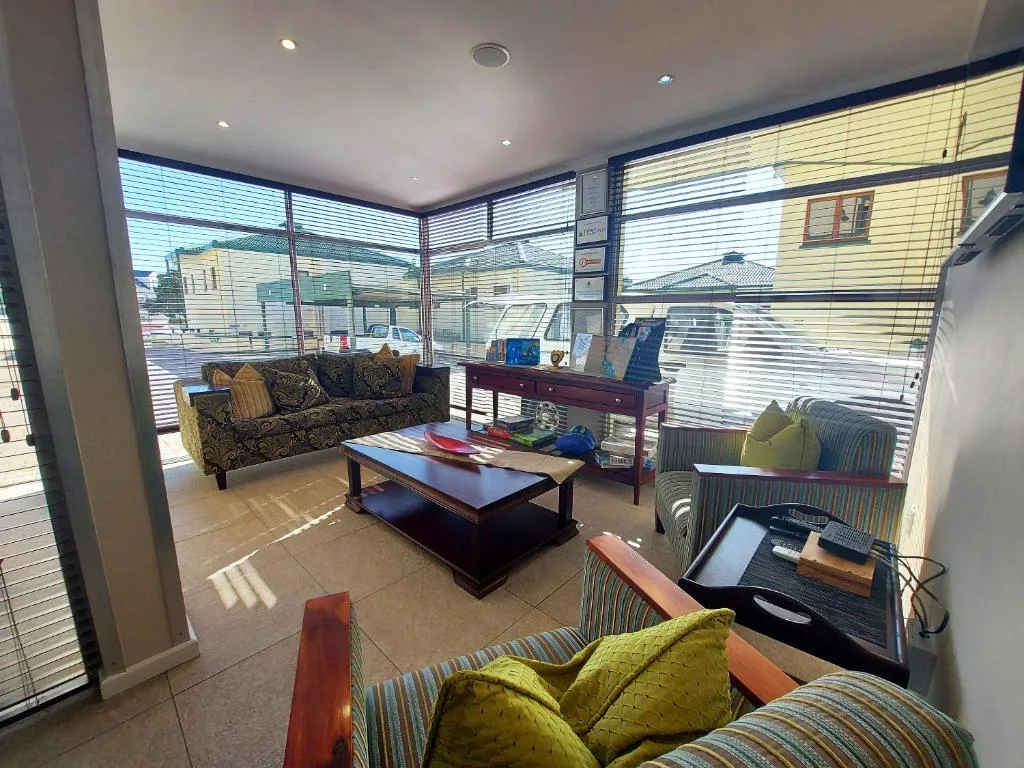 Bright living room with sofas, coffee table, and large windows overlooking neighborhood