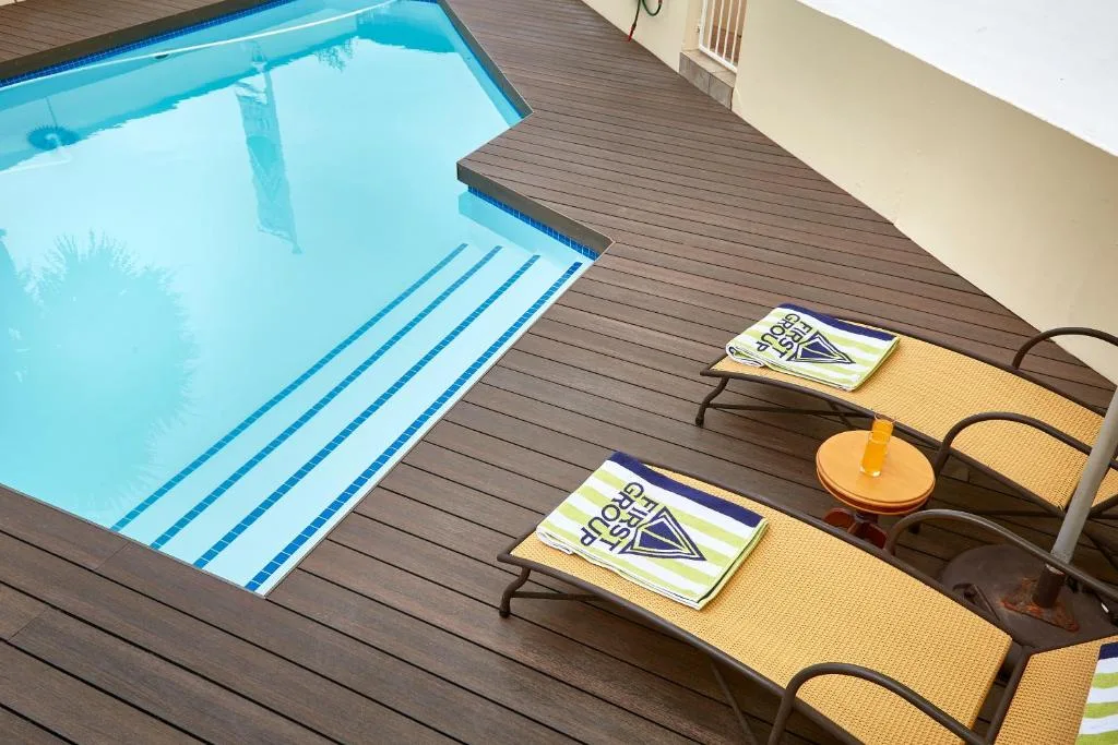 Crystal clear swimming pool with loungers on wooden deck area