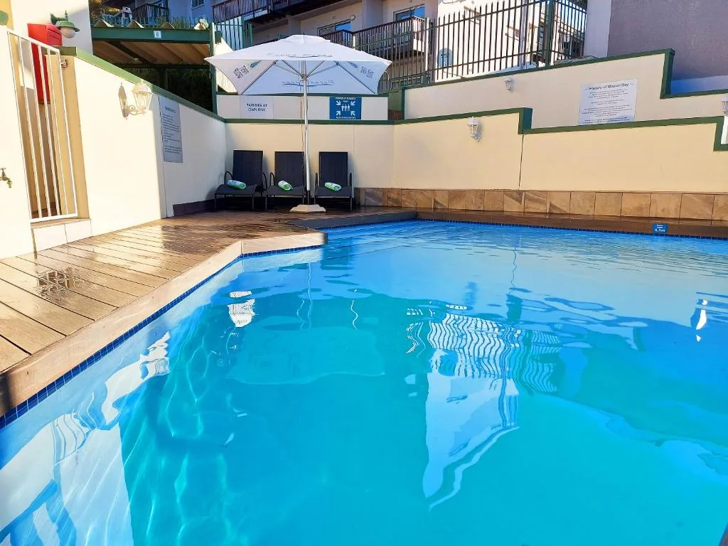 Bright blue indoor swimming pool with wooden deck and loungers