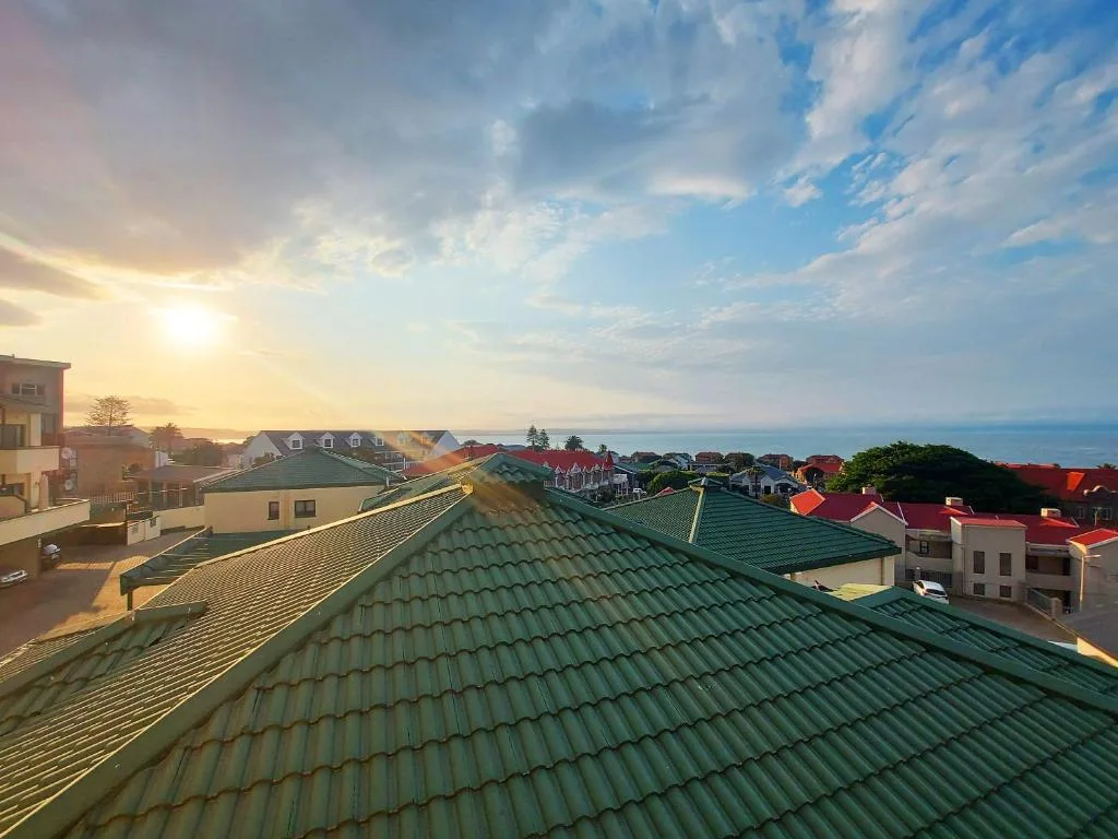 Sunset coastal view over Mossel Bay rooftops toward the ocean horizon