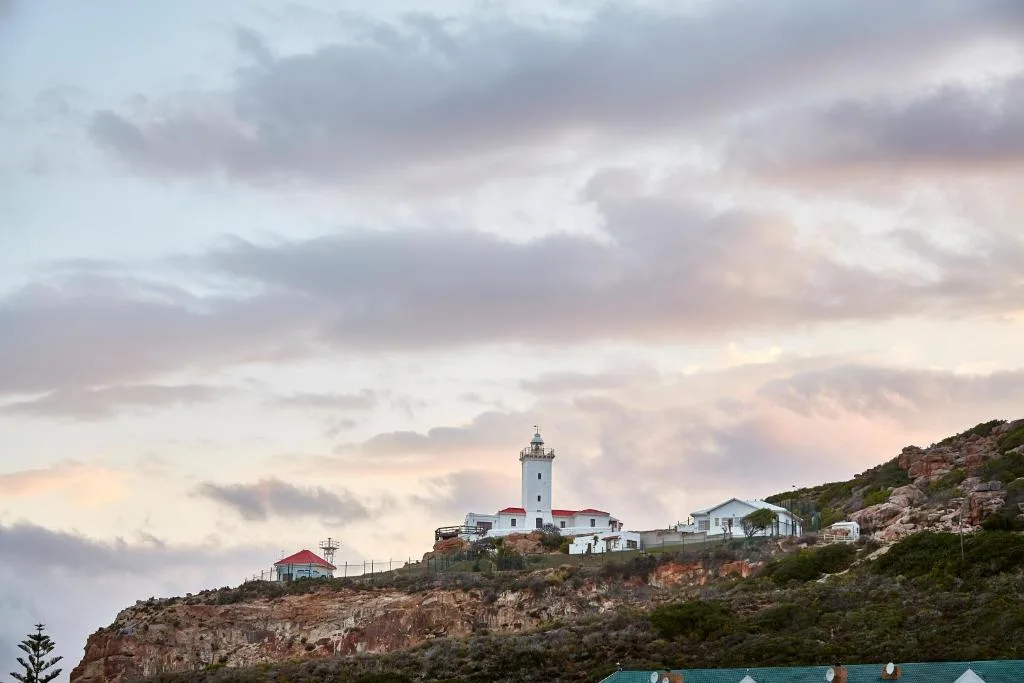 Scenic coastal lighthouse perched on rocky cliff at sunset