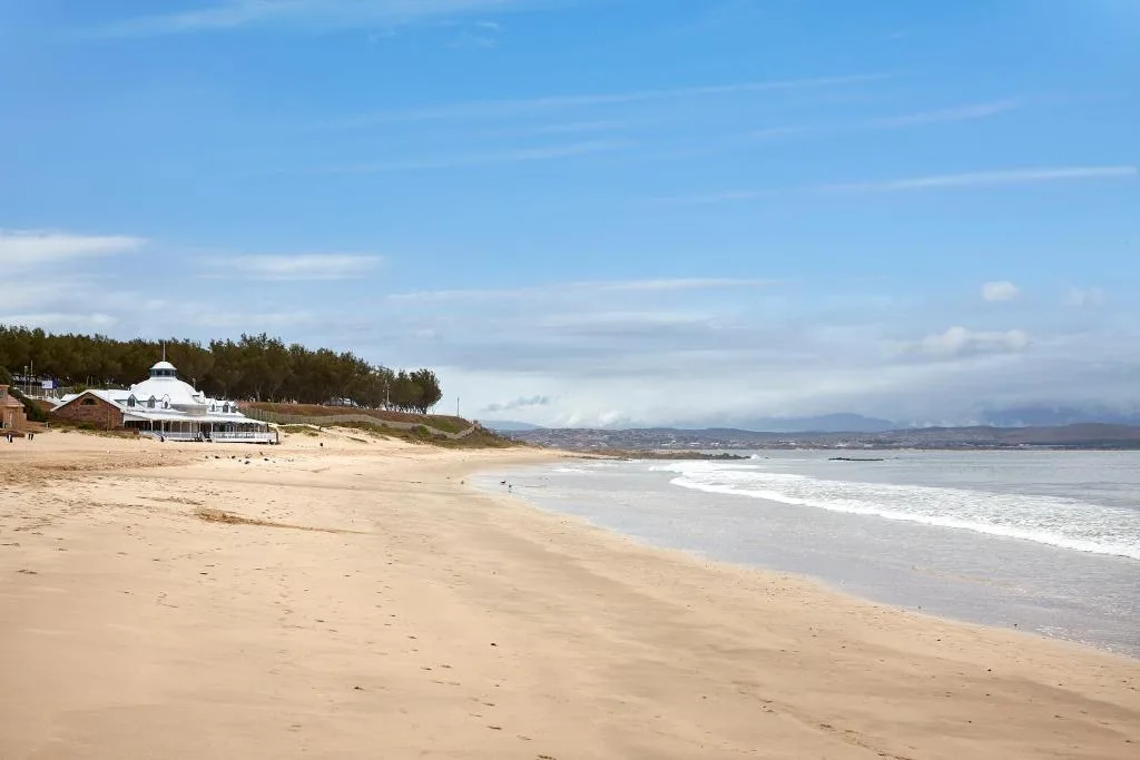 Beachfront property with ocean waves and coastal mountains distant