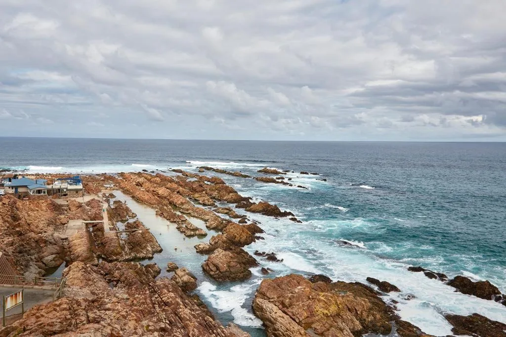 Dramatic coastal view with rocky outcrops, turquoise ocean, and dramatic sky