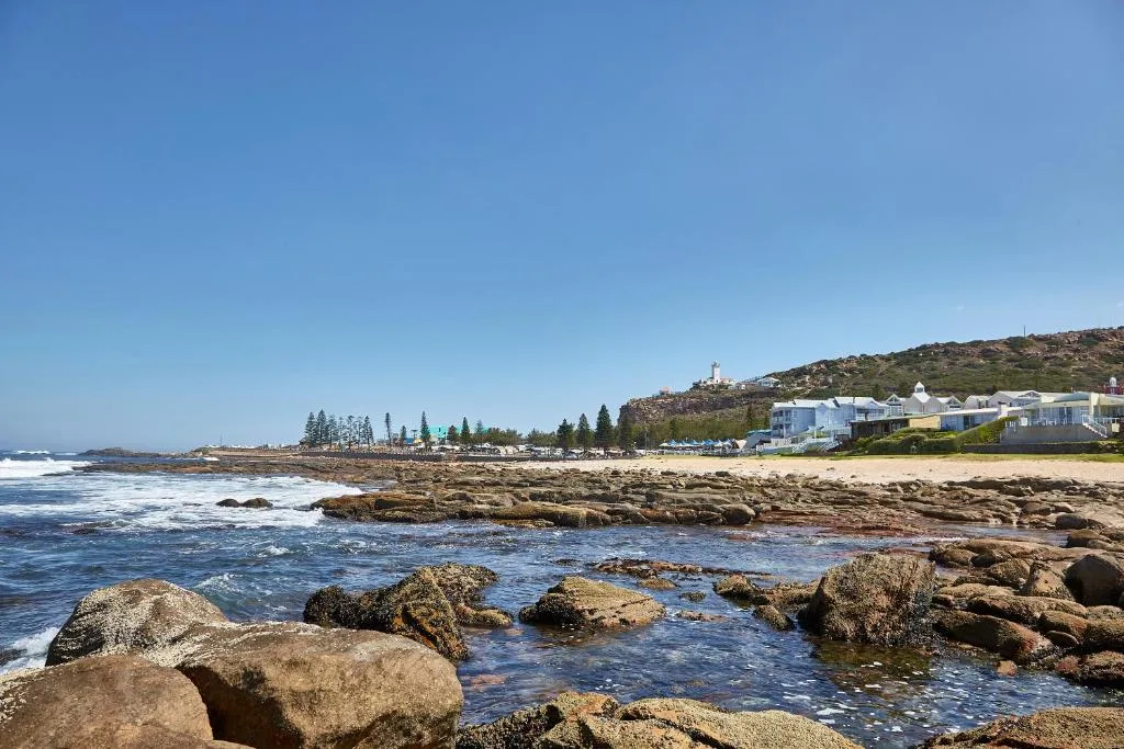 Rocky coastline with ocean waves and beachfront properties on hillside