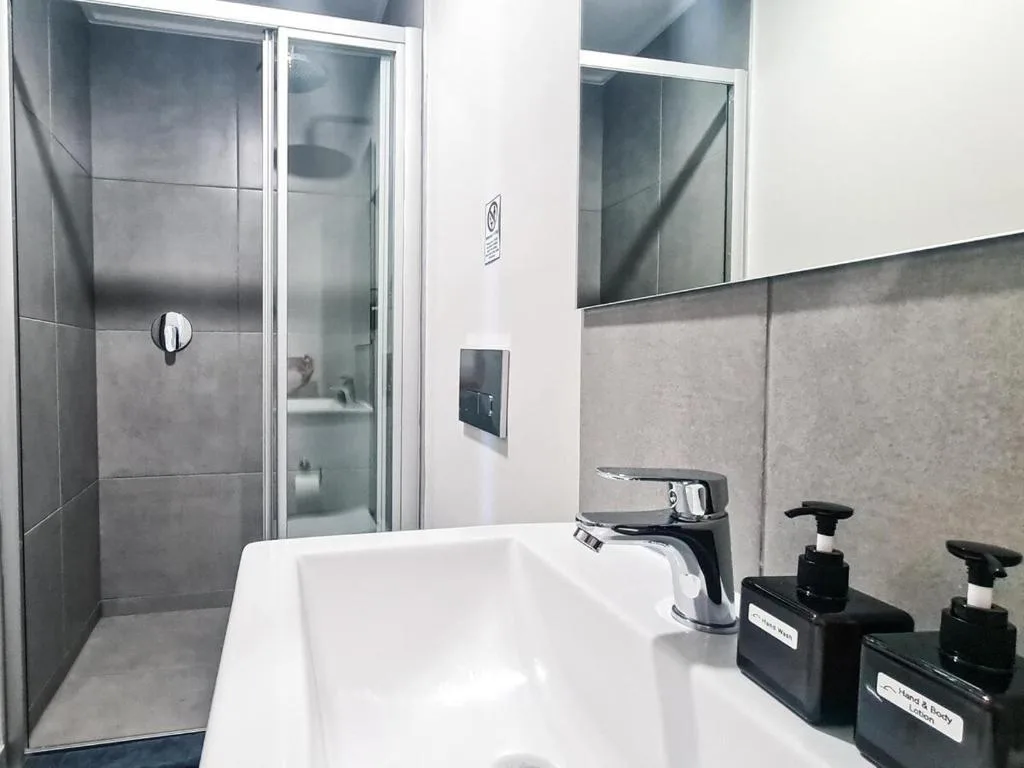 Modern bathroom with white sink, black faucet, and glass shower enclosure