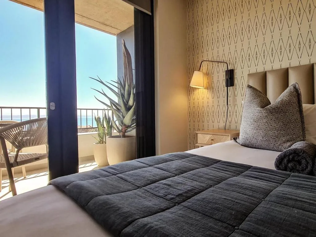 Modern bedroom with ocean view, dark bedding, and coastal plant decoration