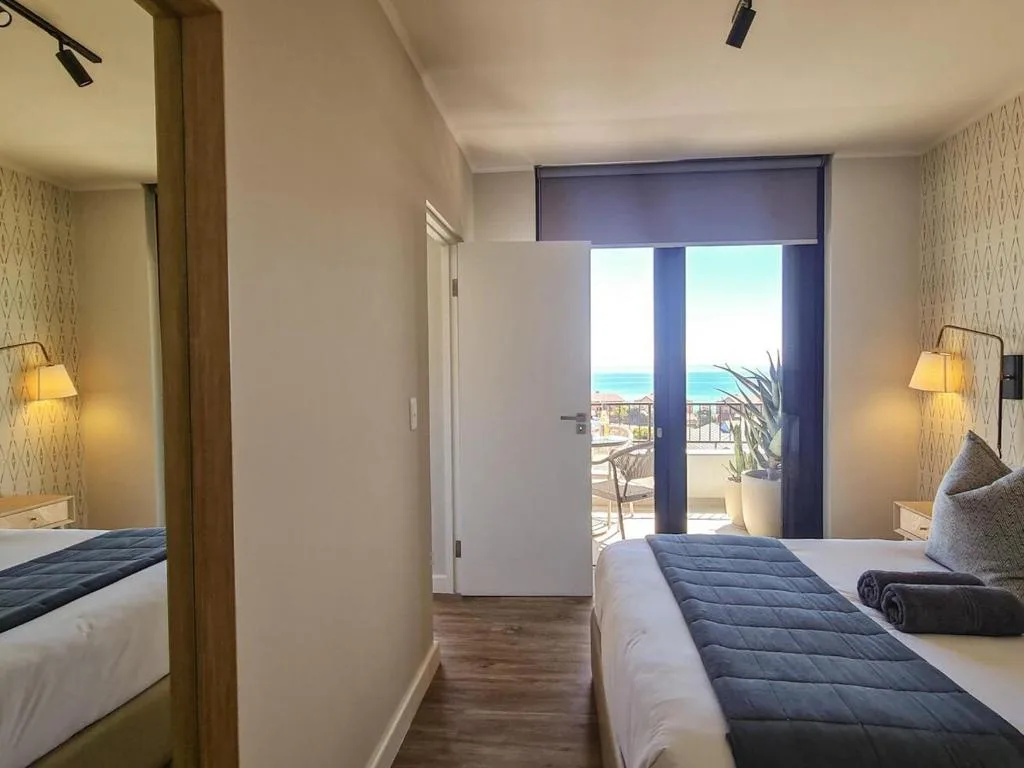 Bright bedroom with twin beds overlooking ocean view through glass doors
