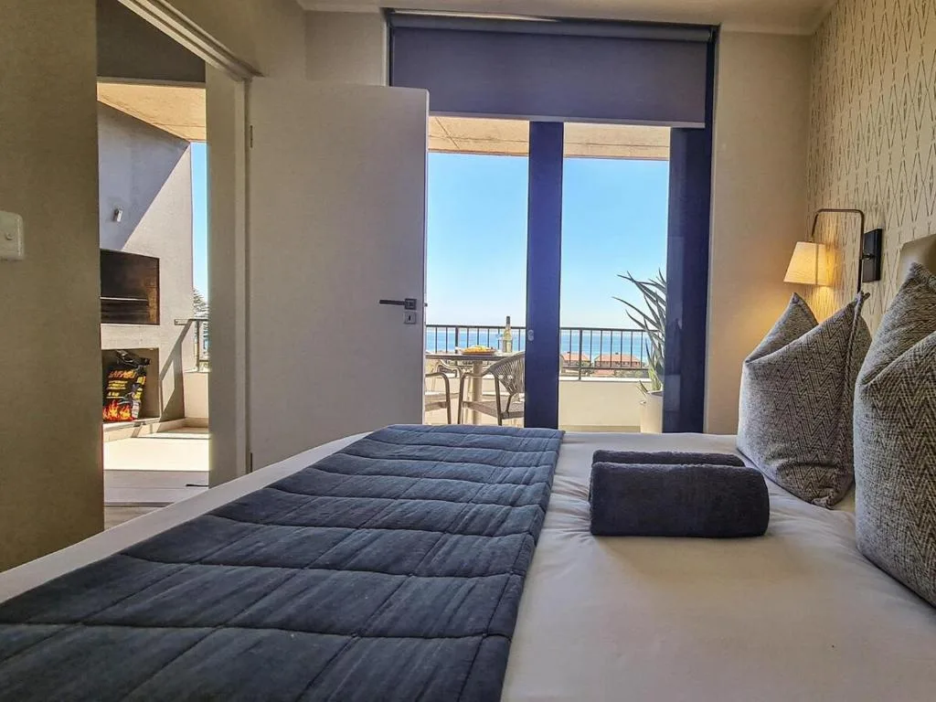 Modern bedroom with ocean view through glass doors and balcony access