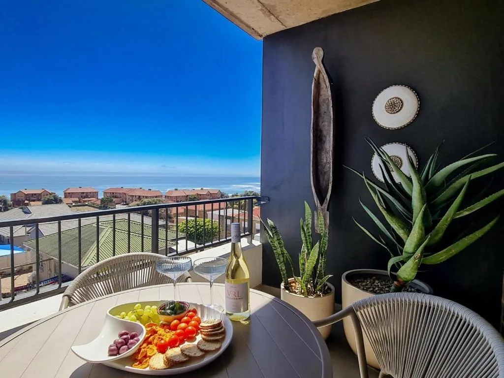 Stylish deck with ocean view, wine, charcuterie, and potted plants
