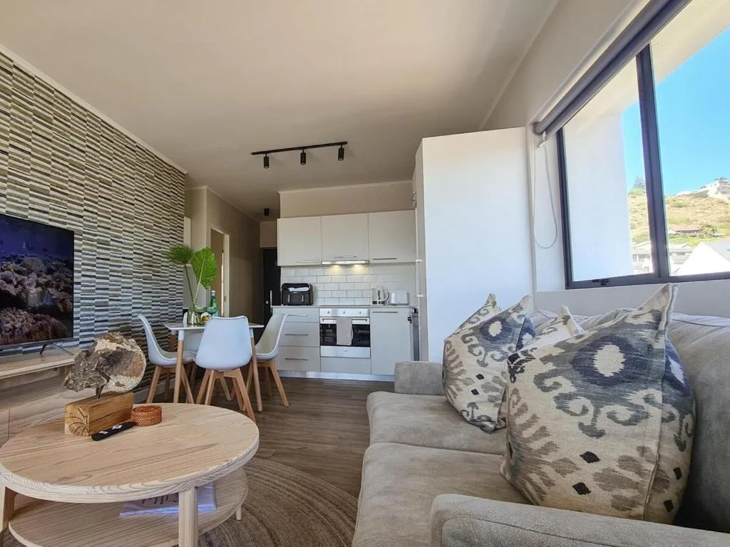 Open-plan lounge with sofa, dining area, and kitchen visible beyond