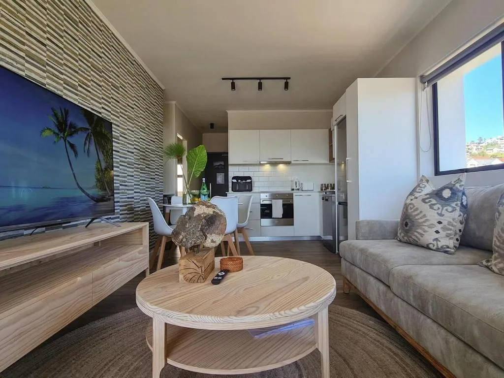 Modern lounge with grey sofa, wooden coffee table, and ocean view window
