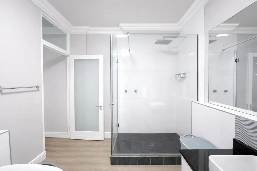 Modern bathroom with walk-in shower, rainfall showerhead, and frameless glass enclosure