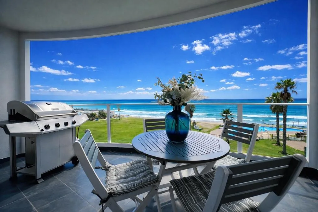 Beachfront deck with braai, dining table, and ocean views on sunny day