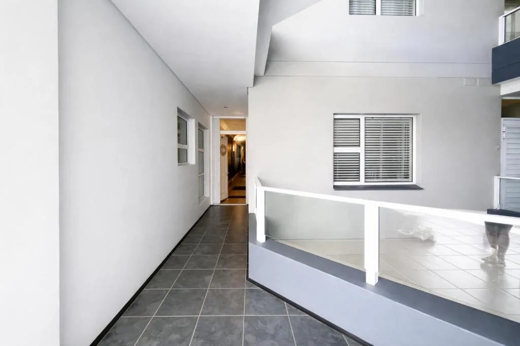 Modern covered balcony with white railings overlooking the property