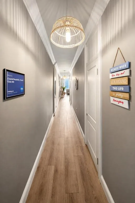 Modern hallway with wooden flooring, pendant lighting, and inspirational wall signage