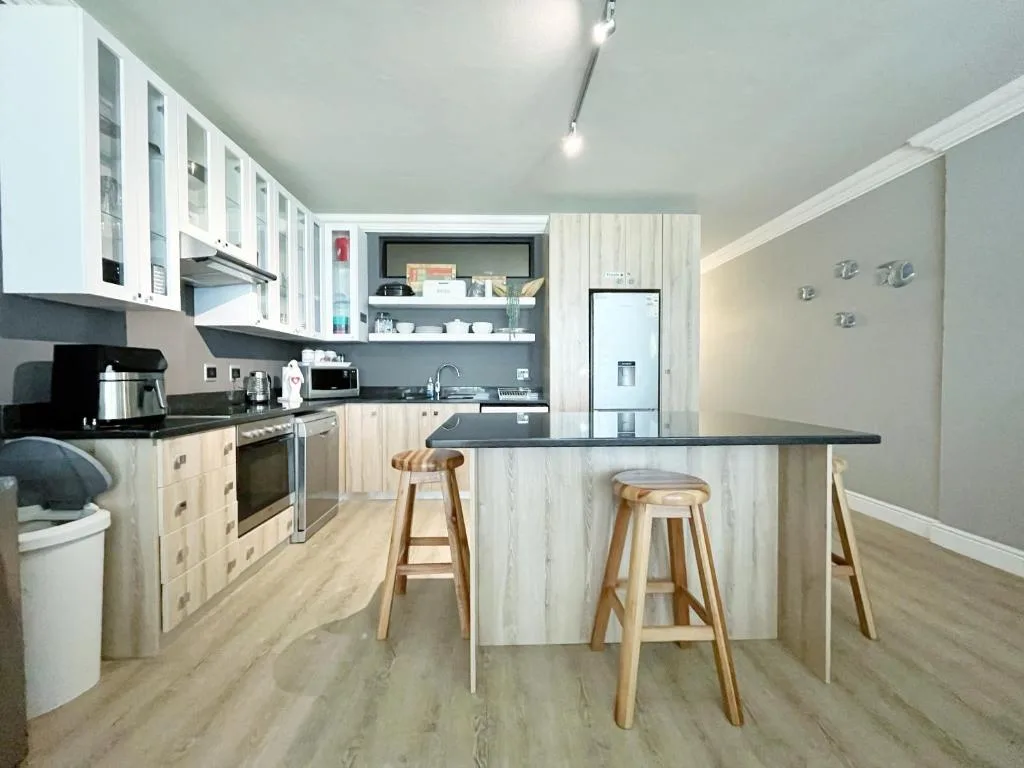 Modern kitchen with white cabinetry, black counters, and wooden bar stools